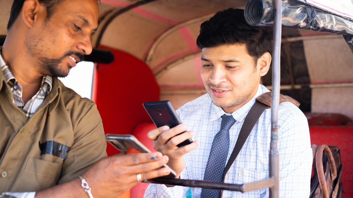 An auto rickshaw driver receives a digital payment from his passenger.