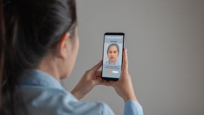 A woman uses facial recognition for identity verification on a smartphone.
