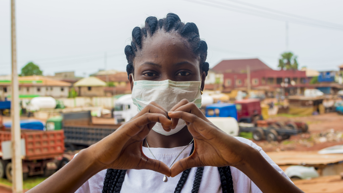 African woman wearing a sanitary masks makes a heart with her hands