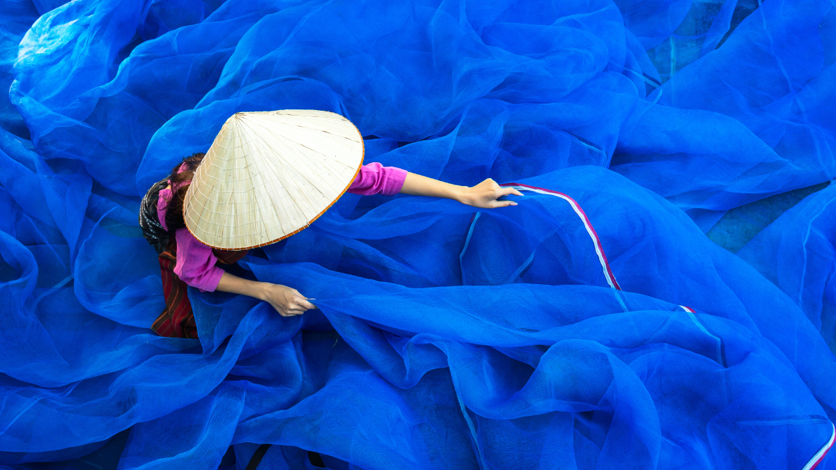 A woman repairs fishing nets in Thailand