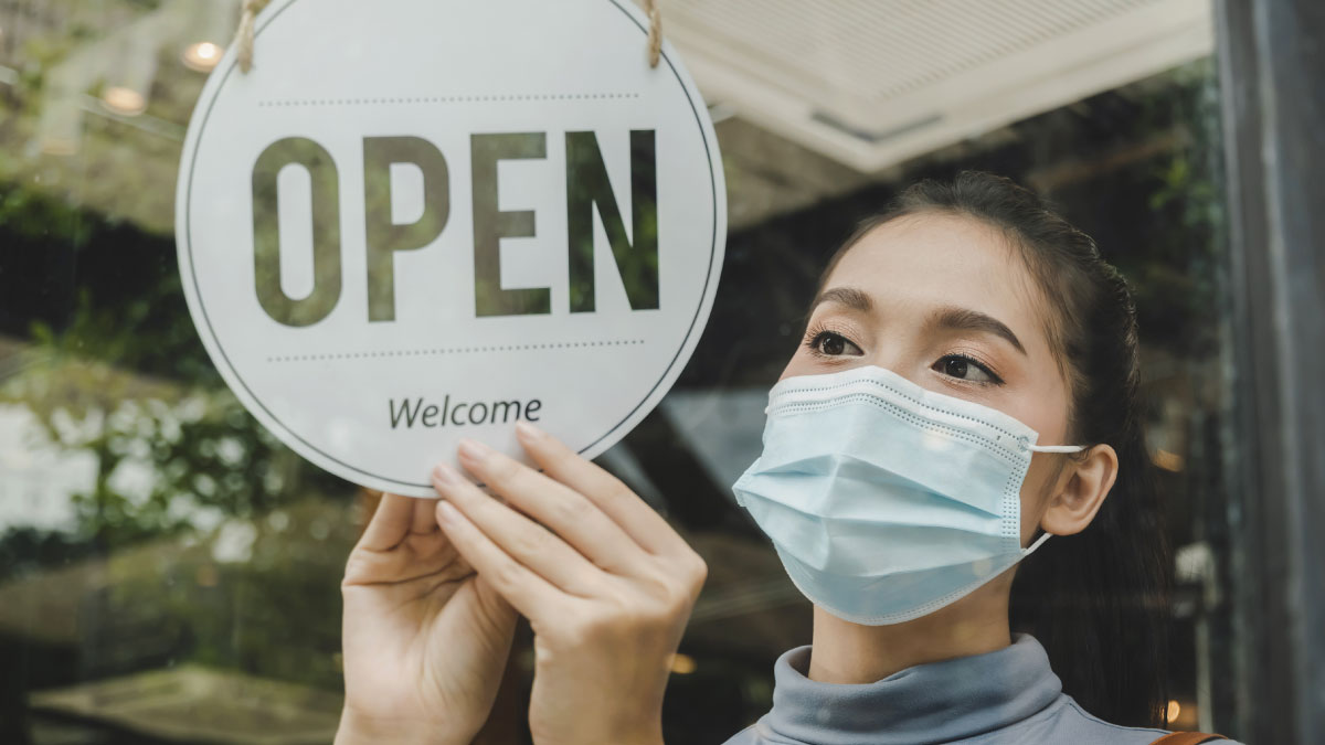 Small business owner hangs an open sign