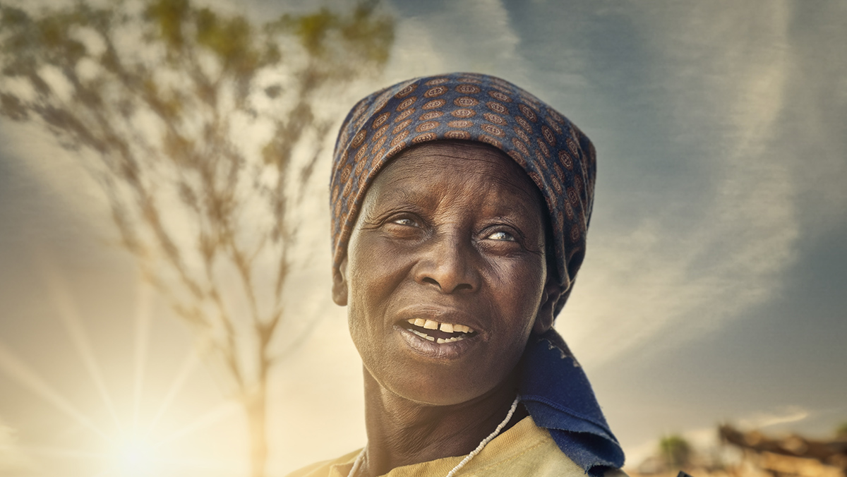 African woman standing in sun-set in front of tree