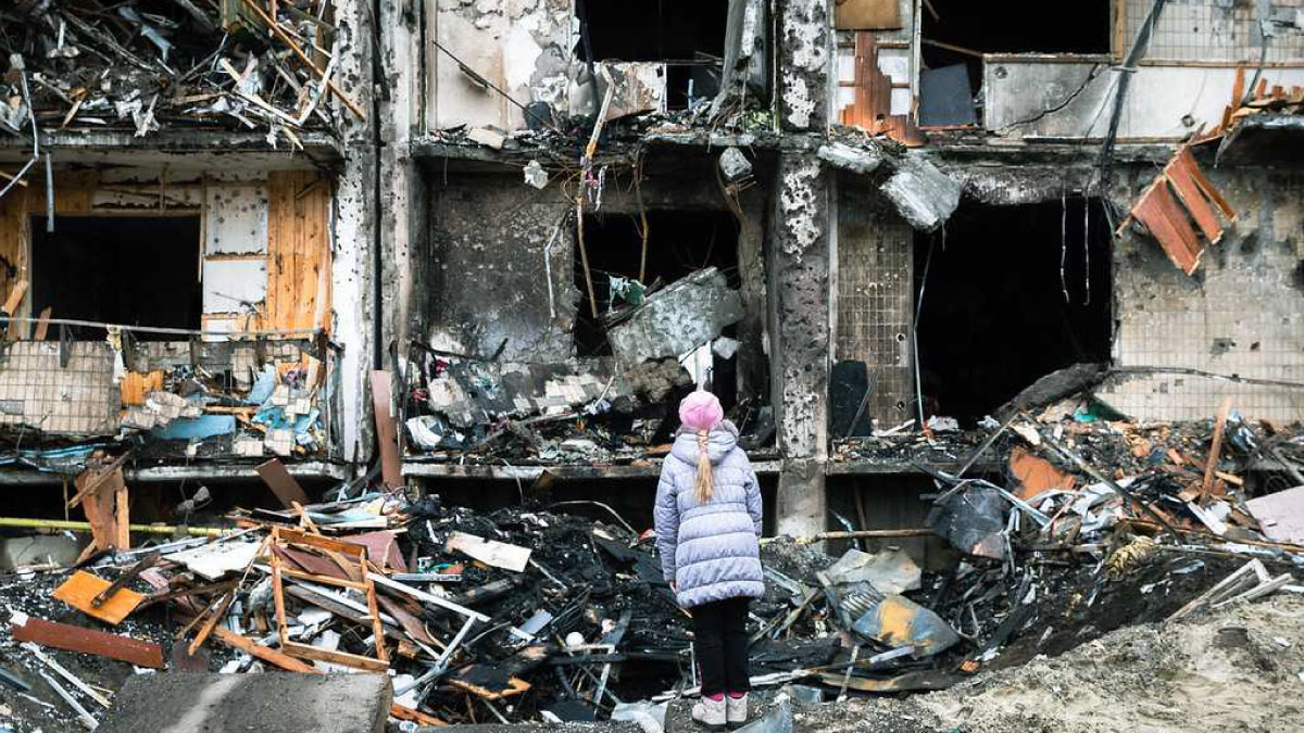 On 25 February 2022 in Kyiv, Ukraine, a girl looks at the crater left by an explosion in front of an apartment building which was heavily damaged during ongoing military operations.