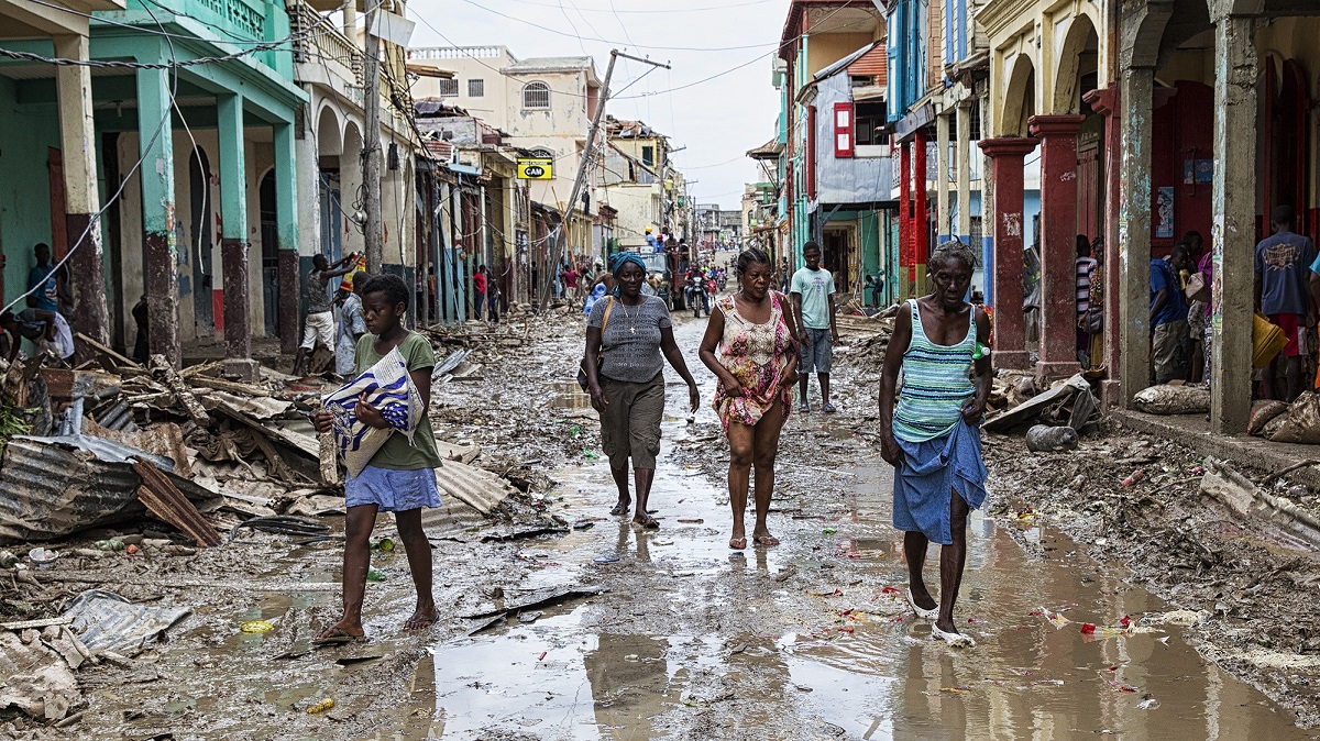 People in Haiti walk through a street in the aftermath of Hurricane Matthew