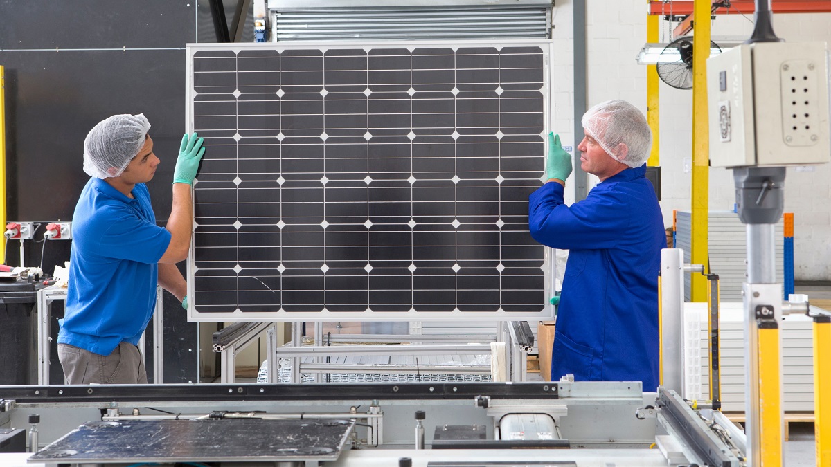 Factory workers lifting new solar panels off the production line