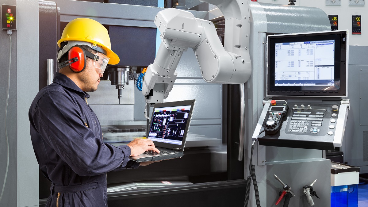 An engineer uses computer automation programmes to control a robotic hand in a smart factory.