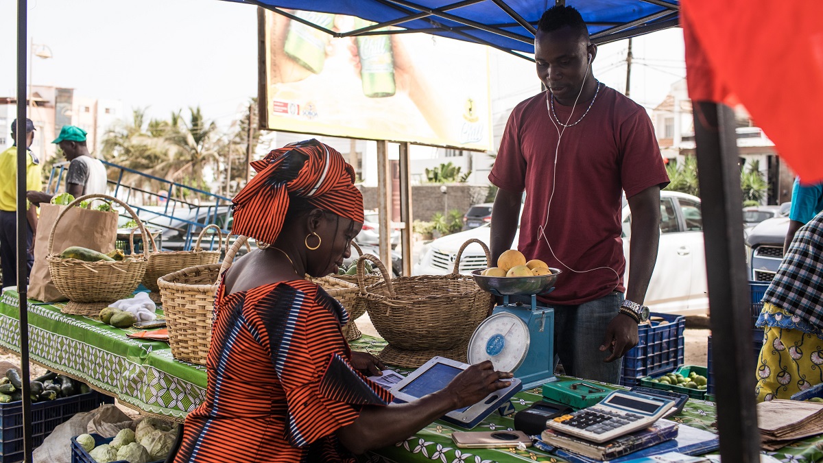 A woman processes a vegetable order using her tablet at a market in Dakar, Senegal.