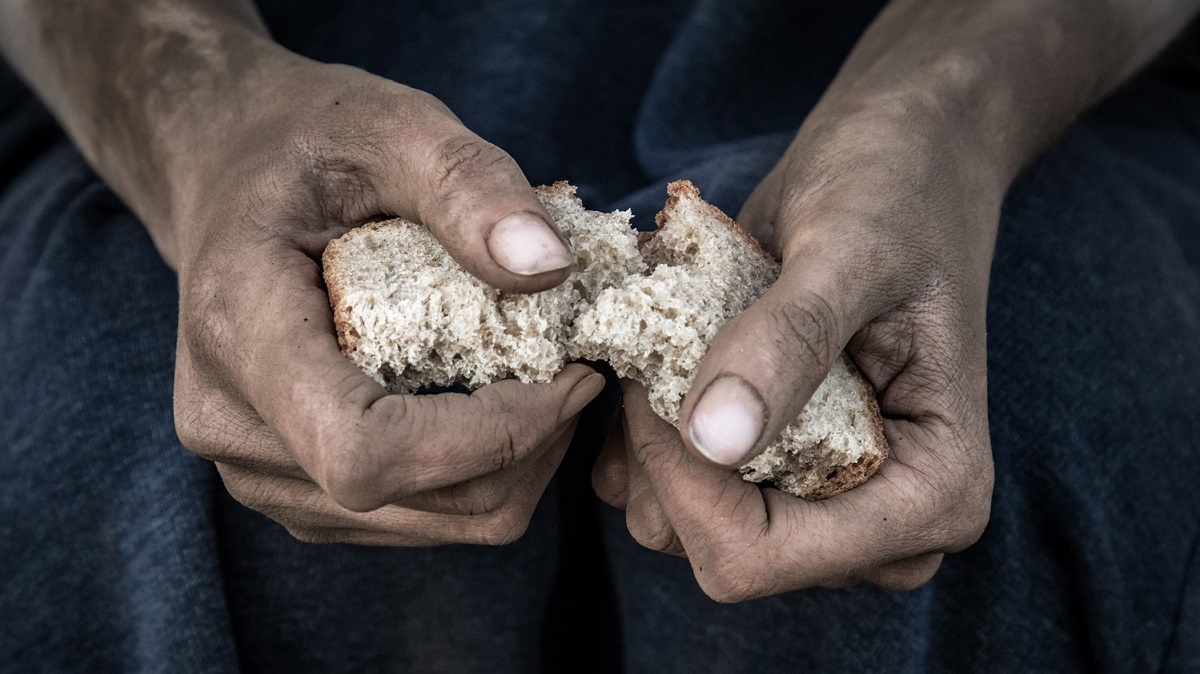 A poor person is breaking bread.