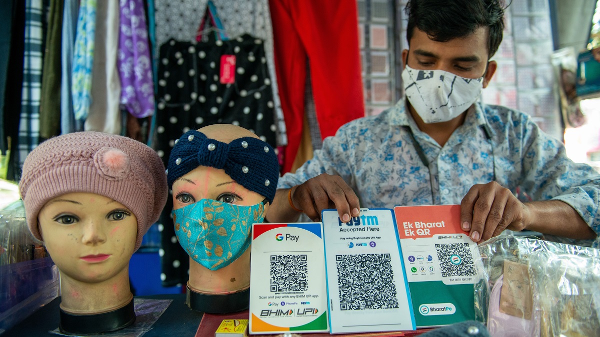 Small business owner in India shows QR code payment options.
