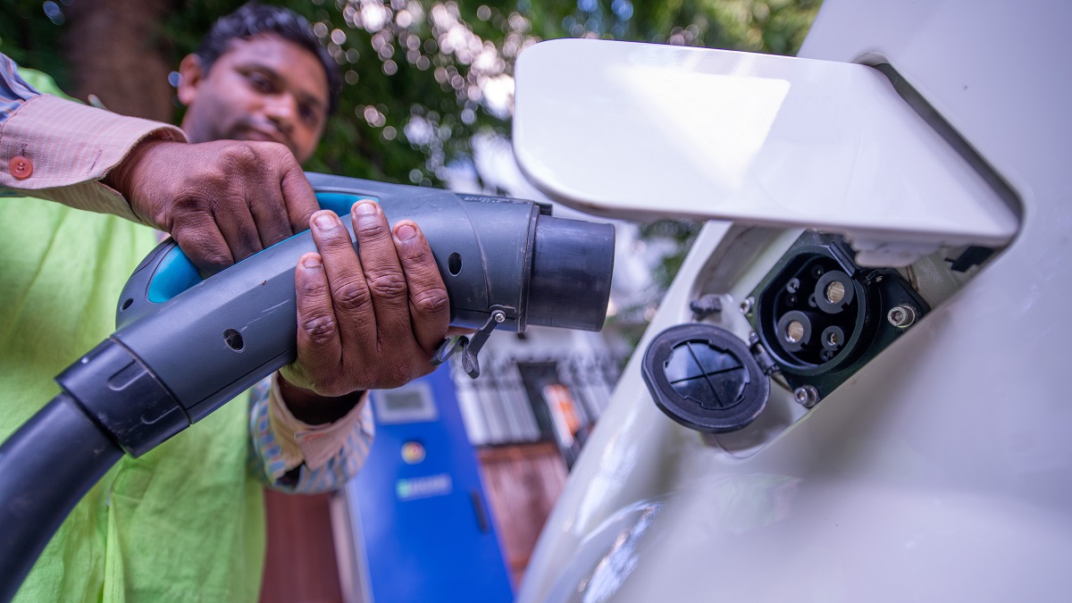 A worker in India charges an electric car