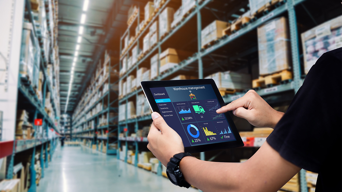 Worker hands holding tablet on blurred warehouse as background