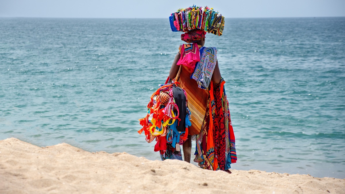 An African businesswoman sells traditional costume fabrics on a beach in Luanda, Angola.