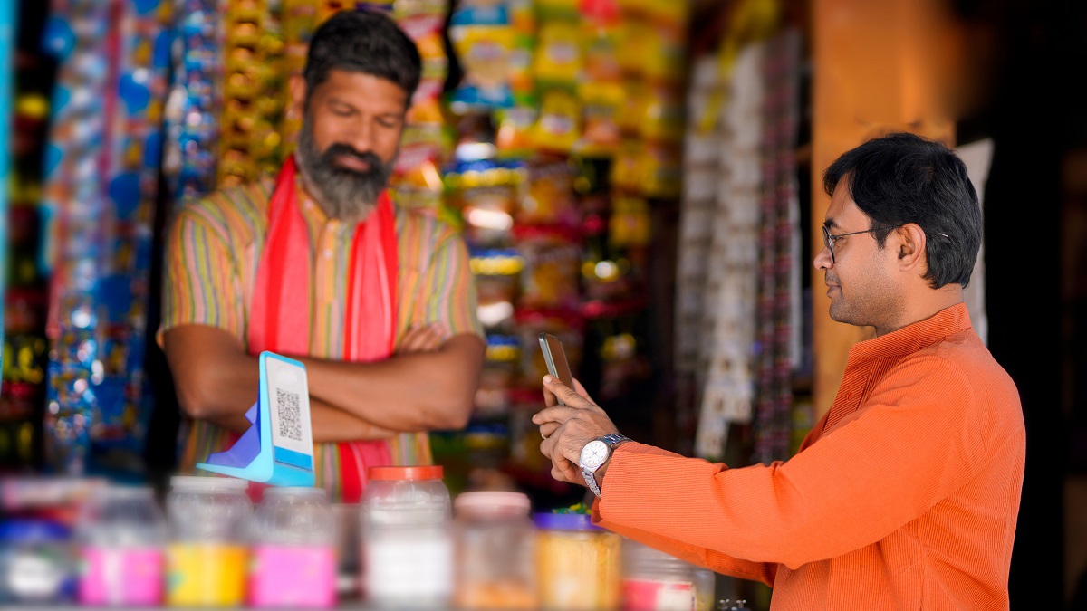 A customer uses his smartphone for digital payment at a groceries shop in rural India.