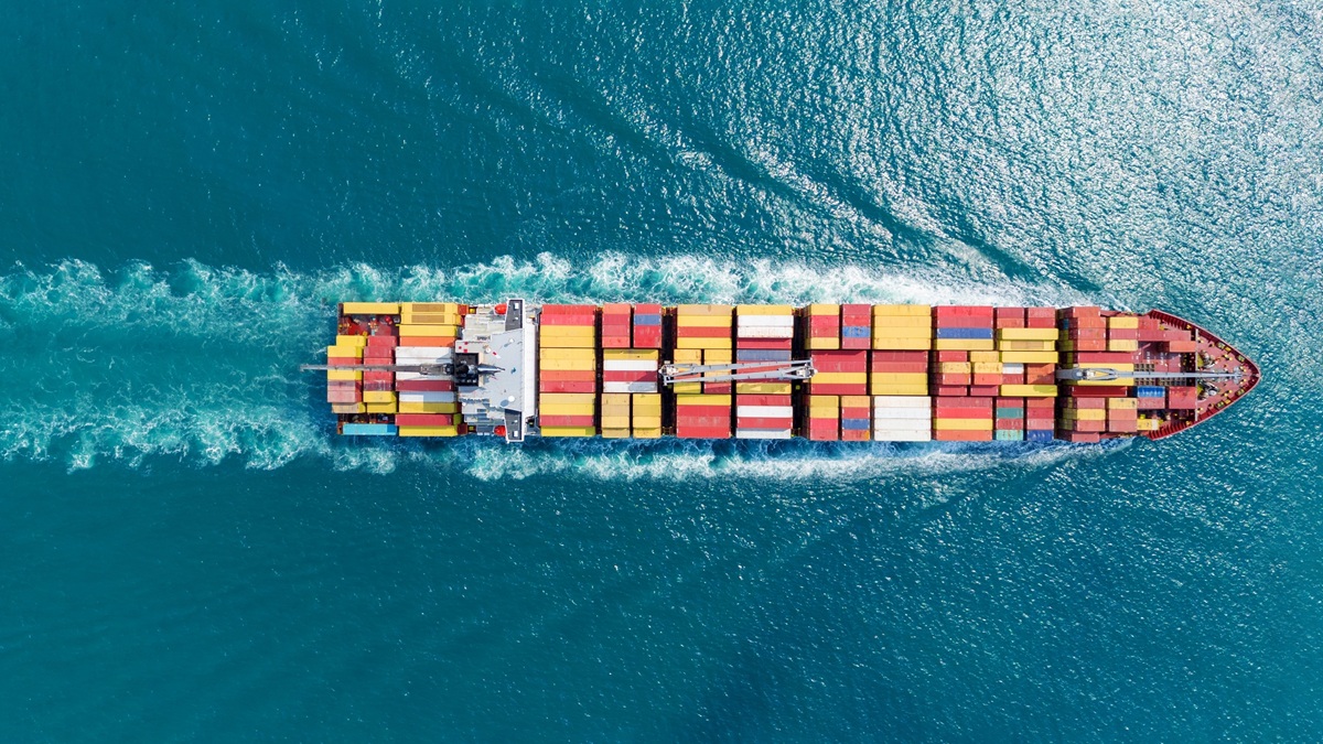 Container ship sailing through turquoise waters.