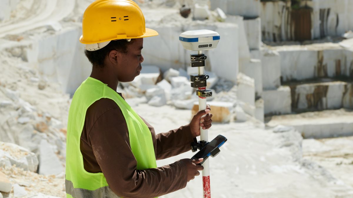 A female surveyor in a mining environment choosing settings of theodolite on territory of marble quarry