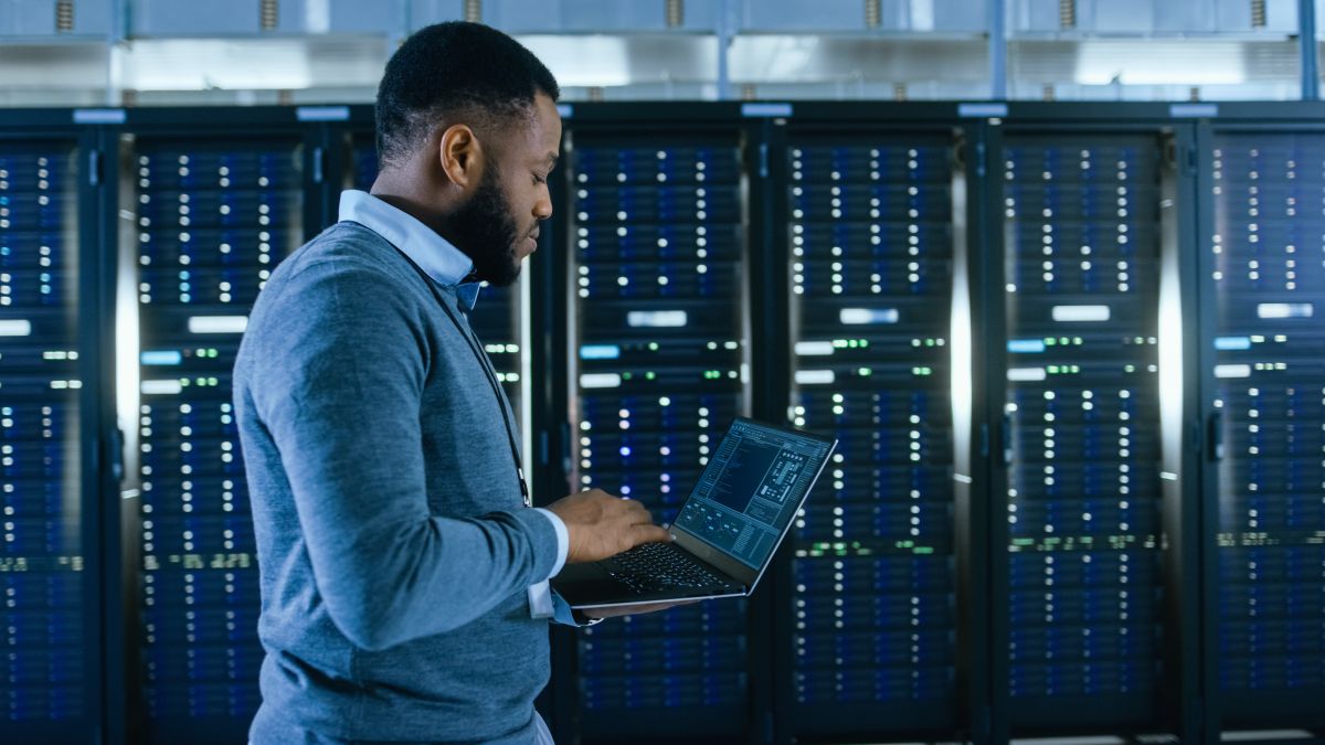Data Center IT Technician Walking Through Server Rack Corridor