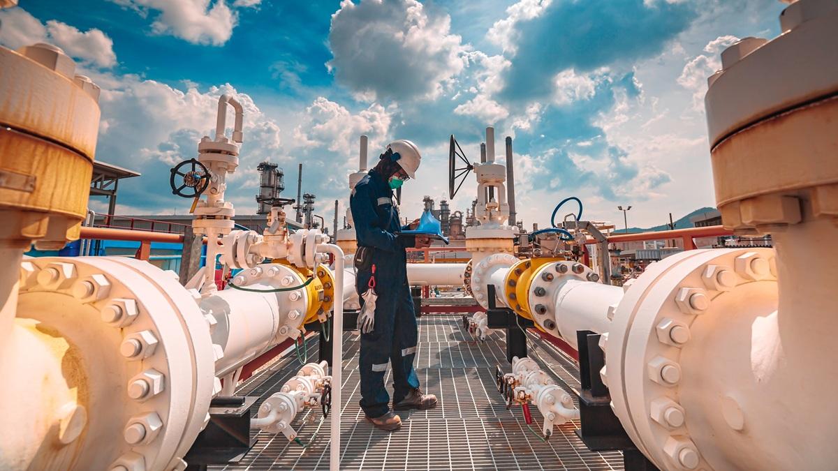 Worker checks pipes at crude oil factory.