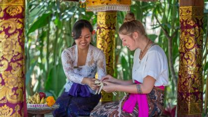 A foreign tourist learns traditional craftsmanship from a member of the local community in Bali, Indonesia.