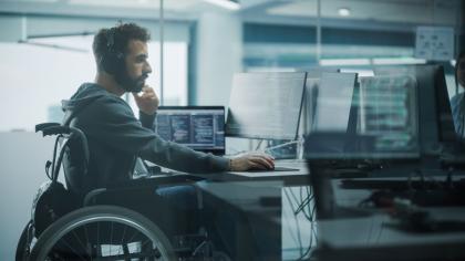 A man in a wheel chair works on a computer