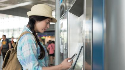 A woman buys train tickets from a self-service machine.