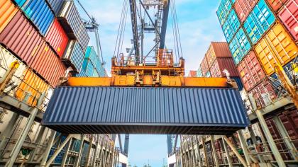 A crane lowers a container in the hull of a ship.