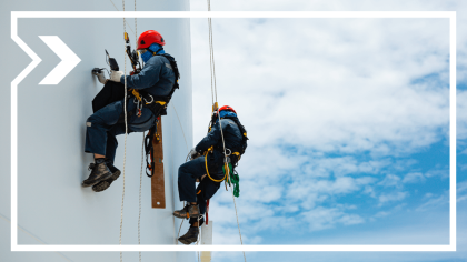 Two workers pain the side of a ship