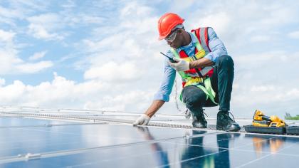 An engineer maintains solar cell panels on a rooftop.