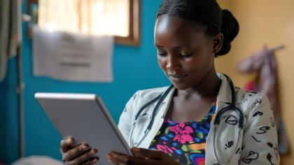 Healthcare worker wearing a stethoscope uses a tablet in a clinic in Uganda.
